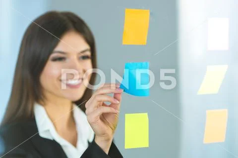 The smile woman glues a sticker on the glass Stock Photos
