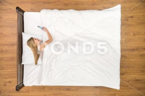 The smile woman lay on the bed and phone. View from above Stock Photos