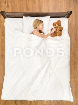 The smile woman lay on the bed with the soft toy. View from above Stock Photos