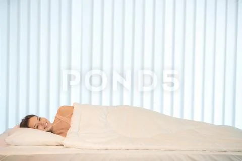 The smile woman lay in the bed with a white linens Stock Photos