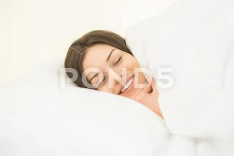 The smile woman sleeping in the white linens Stock Photos