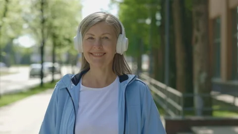 Smiled elderly woman looking at the camera while listen to music using Stock Footage 220602878