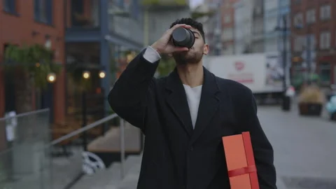 Smiled multi ethnic man is walking on the street holding the new year gift and Stock Footage 224345277