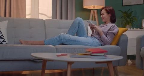 Smiled young red-haired beautiful woman lying on the cozy sofa at home and Stock Footage 122500322
