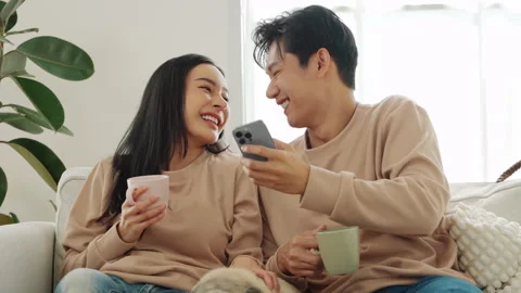 Smiles and laughter shared between couple while enjoying drinks in cozy living Stock Footage 300018305