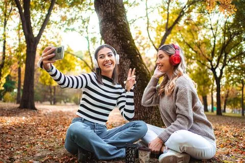 Smiles and memories shared by two girls in a cozy autumn park setting Stock Photos
