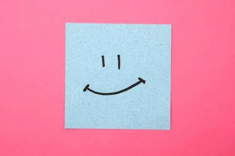 Smiley face on blue sticky note on pink background Stock Photos