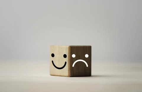 Smiley face on bright side and sadness on dark side of wooden cube block Stock Photos
