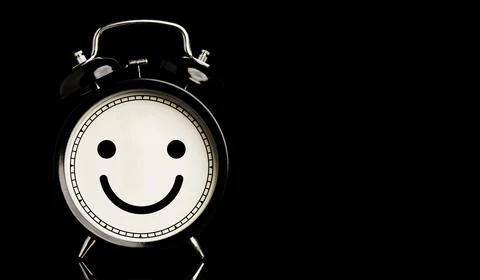 Smiley face inside of alarm clock on black background and copy space Stock Photos