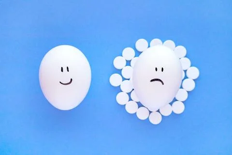 Smiley faces on eggs and white aspirin tablets next to them.  Stock Photos