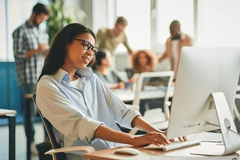 Smiley female office worker using computer at desk Stock Photos