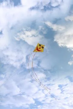 Smiley kite in the clouds Stock Photos