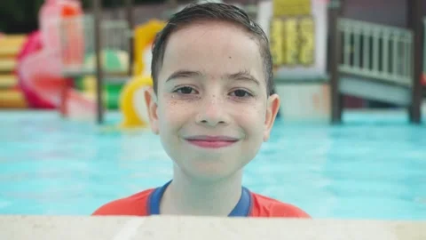 Smiling 10 Year Old Boy Portrait Looking at Camera in Swimming Pool 動画素材 340773945