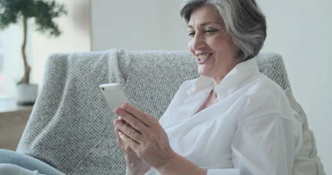 Smiling 60s older senior middle-aged adult lady enjoying mobile for video Video stock 161993353