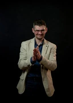 Smiling actor in beige jacket poses clapping hands closeup Stock Photos