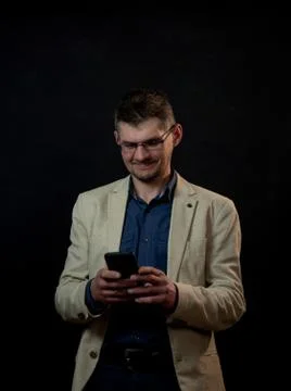 Smiling actor with tree-day stubble sends message by phone Stock Photos