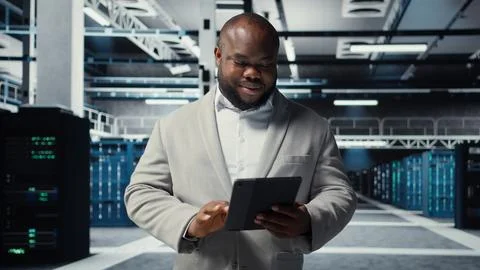 Smiling admin using tablet in in data center maintaining infrastructure Stock Photos