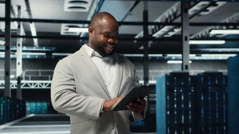 Smiling admin using tablet in in data center maintaining infrastructure Stock Photos