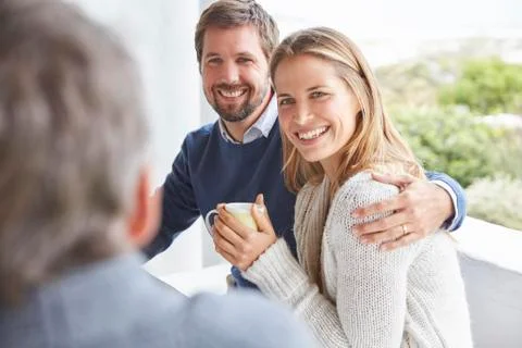 Smiling affectionate couple hugging and drinking coffee on patio Stock Photos