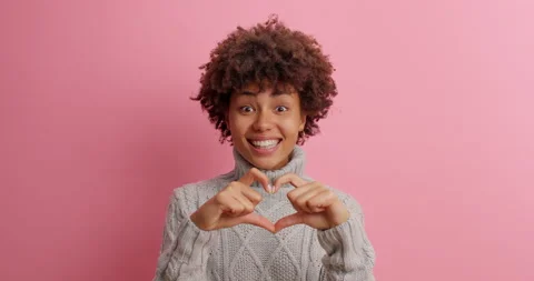 Smiling affectionate dark skinned woman makes heart gesture demonstrates love Stock Footage 142748089