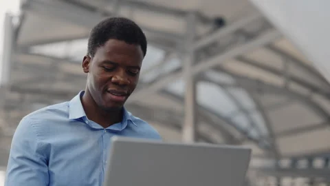 Smiling African American Guy Distant Working on the Laptop from the Outside Stock Footage 259859412