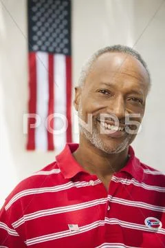 Smiling African American man standing near American flag Stock Photos