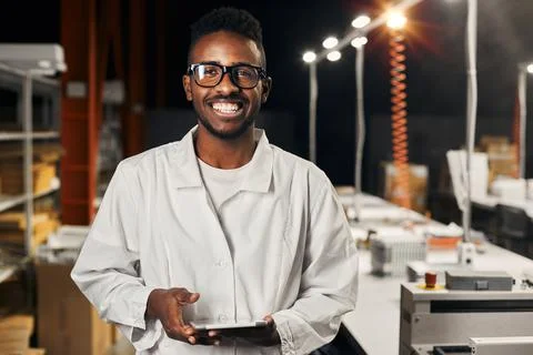 Smiling african engineer working with tablet at factory Stock Photos