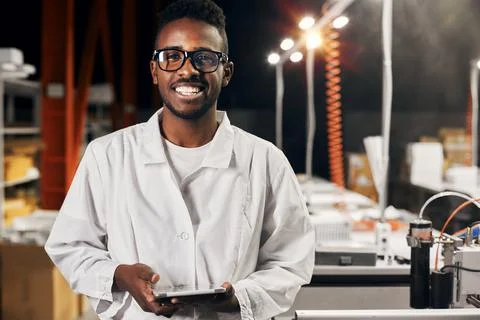 Smiling african engineer working with tablet at factory Foto stock