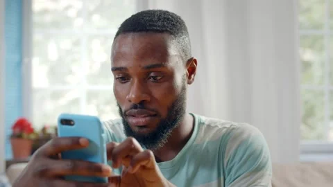 Smiling african man looking into smart phone indoors Stock Footage 133046086