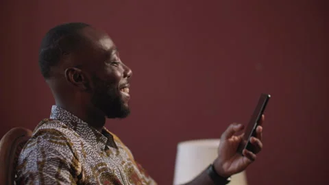 Smiling African Man Using Smartphone at Home. Video stock 345753886