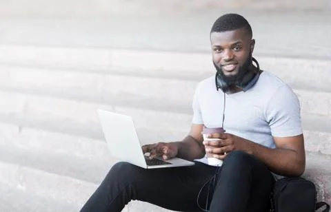 Smiling african student coding outdoor and drinking coffee Stock-Fotos