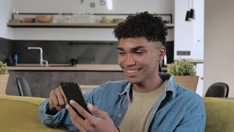 Smiling African student guy having positive emotions looking on smartphone Stock Footage 142575177