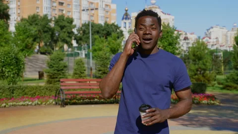 Smiling Afro-American man talking on mobile phone holding paper cup for coffee Stock Footage 162659513