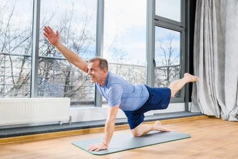 Smiling aged man on mat exercise indoors Stock Photos