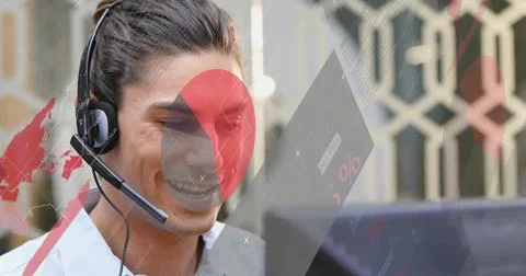 Smiling agent wearing headset and viewing monitor at office with digital 스톡 사진