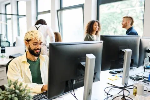 Smiling alternative young man using computer in a coworking Stock Photos