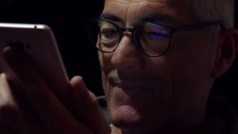 Smiling amusing mid aged man using mobile phone in the night at home Stock-Footage 74430998