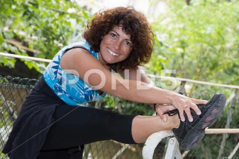 Smiling and cheerful woman stretching leg outdoors Stock Photos
