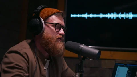 Smiling and gesturing radio host with headphones reading news into studio Stock Footage 263742982