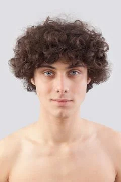 Smiling and handsome, a young man with curly hair, he looks into the camera.. Foto stock