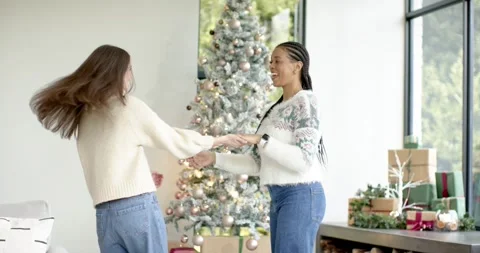Smiling and joining hands Diverse female friends dancing near Christmas tree at Stock Footage 335130725