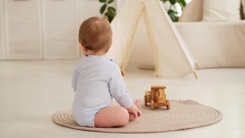 A smiling and joyful kid is crawling on the floor near the wigwam in the Stock Footage 303410635