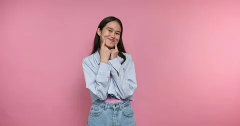 Smiling and posing in front of a pink background in a simple and fun way at.. 動画素材 328247025