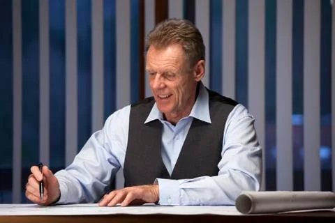 Smiling architect or engineer working in an office in the evening or at night Stock Photos