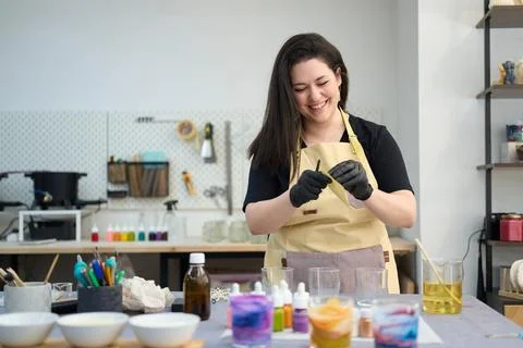 Smiling artisan preparing wax sheets for handmade candles in craft studio Stock Photos