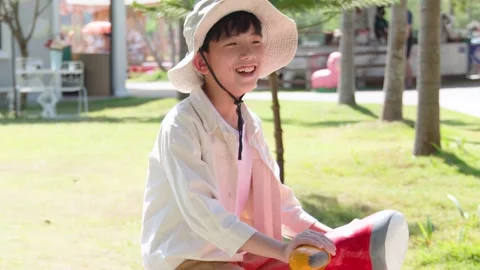 Smiling Asian Boy in Safari Hat Sitting on Red Scooter Statue Stock Footage 335675727