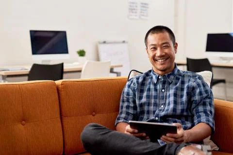 Smiling Asian designer using on a digital tablet at work Foto stock