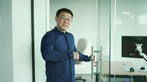 Smiling asian IT specialist programmer looking at camera and showing inviting  Stock Footage 225736088