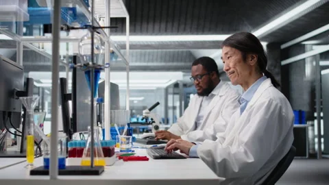 Smiling Asian laboratory researcher using computer to process DNA patient data Stock Footage 320146213