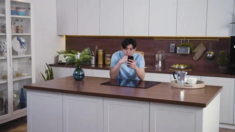 Smiling asian man starts talking on video conference using smartphone. Young guy Stock Footage 153476917